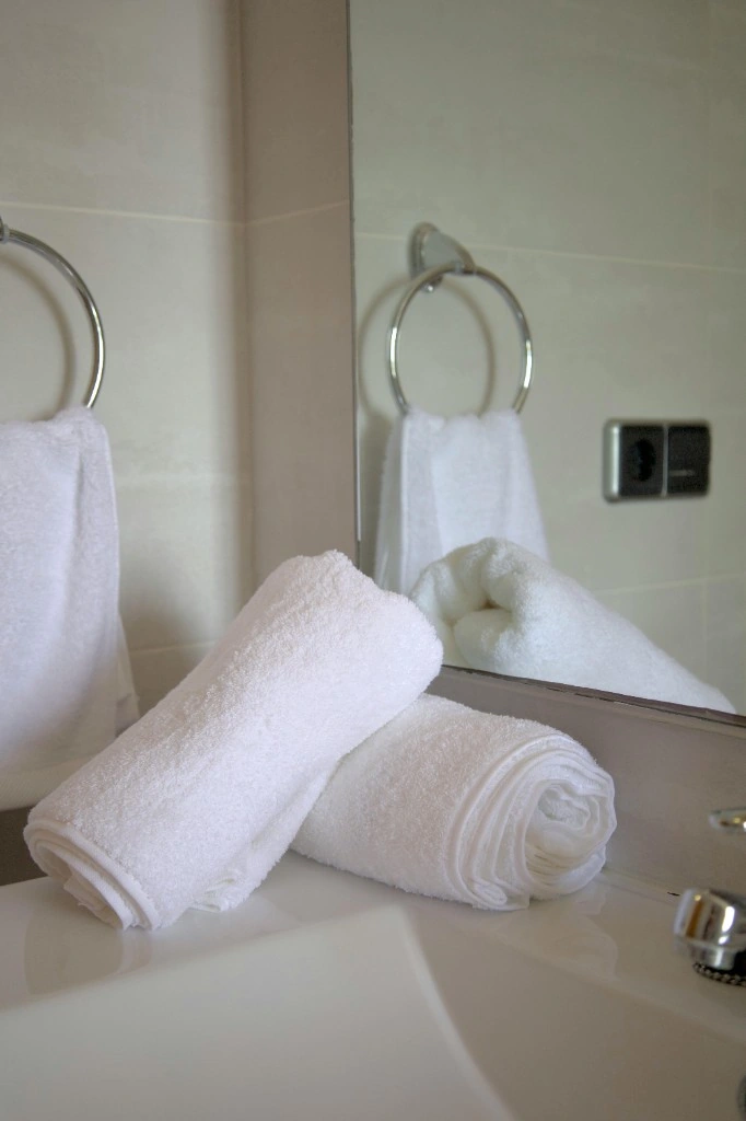 Neatly rolled white towels and streak-free bathroom mirror